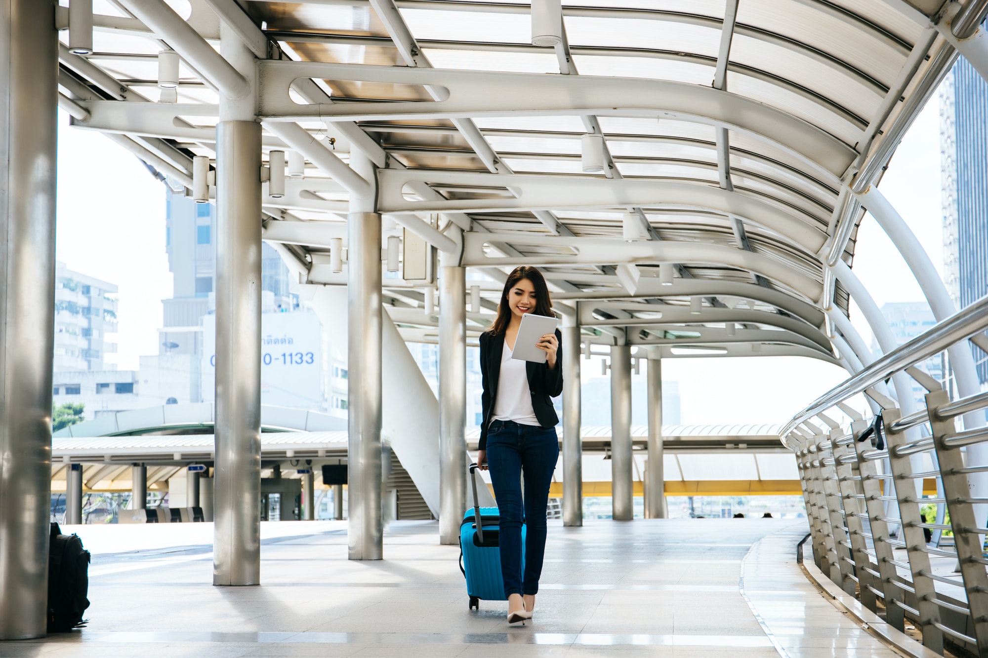 businesswoman walking outside public transportation station businesswoman traveler with suitcase